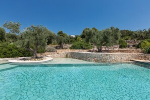 A clear blue pool with stone tiles, surrounded by olive trees and a stone wall. - Villa Rio (Patu)