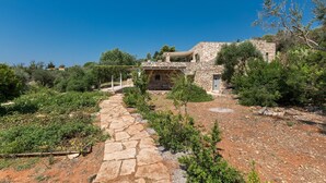 A stone building with a stone pathway leading to it, surrounded by greenery and trees. - Villa Rio (Patu)