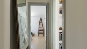 A hallway with a wooden ladder, a white door, and a bookshelf with books. - Villa Rio (Patu)