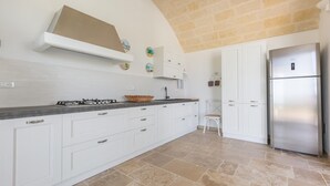 Una cocina moderna con armarios blancos, un refrigerador de acero inoxidable y una estufa a gas.
