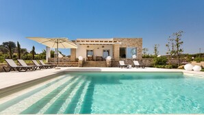 Un área de piscina con sillones de descanso y una pérgola.