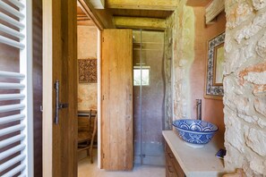 Un bagno con una porta in legno, una cabina doccia in vetro e un lavabo azzurro con decorazioni.