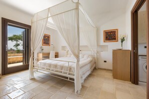 Un letto a baldacchino con tende a baldacchino e vista sull'esterno attraverso una porta vetrata.