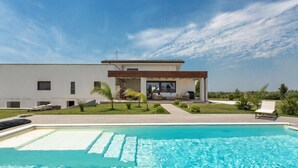 Una casa moderna con piscina, un patio y un césped bien cuidado.