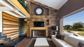 Una sala de estar moderna con chimenea, un reloj grande y un sofá.