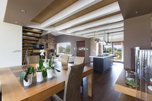 A modern kitchen with a central island, wooden flooring, and a dining area with a wooden table and chairs.