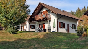 Une maison à deux étages avec un balcon, une cheminée et une pelouse.