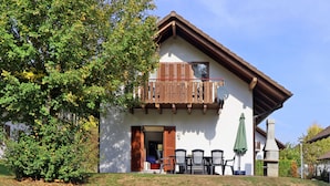 Une maison à deux étages avec un balcon, une cheminée et un espace salon extérieur.