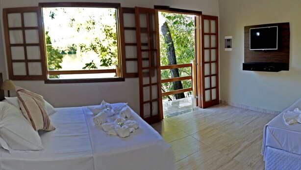 Habitación de hotel con cama, televisión, ventana que ofrece vistas a zonas verdes y puerta de acceso al exterior.