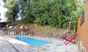 Una piscina al aire libre, sombrillas, sillones reclinables de piscina