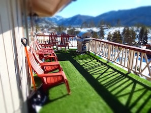 Een balkon met rode stoelen en een tafel, uitkijkend op een besneeerd landschap met bergen.