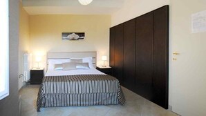 Une chambre à coucher avec un grand lit, une armoire en bois foncé et un seul luminaire.