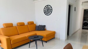 Ein modernes Wohnzimmer mit einem Ecksofa, einem kleinen runden Tisch und einer Wanduhr.