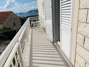 A balcony with a view of the sea and mountains, white railings, and a door. - Apartments Dupcic Cavtat (Konavle)