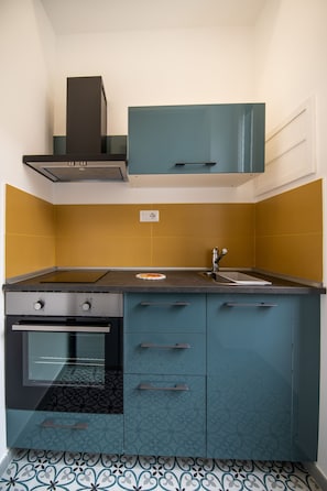A compact kitchen with a stove, oven, sink, and teal cabinets. - Salerno 1950 (Salerno)