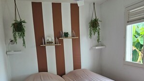 Ein Zimmer mit zwei Betten, einem Deckenventilator und Regalen mit Pflanzen.