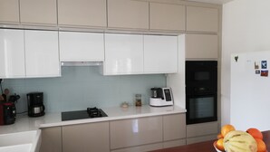 Eine moderne Küche mit weißen Schränken, einem schwarzen Backofen, einer Kaffeemaschine und einer Obstschale auf der Arbeitsfläche.