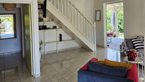 Ein großzügiger Wohnbereich mit Treppe, Deckenventilator und Blick ins Freie.