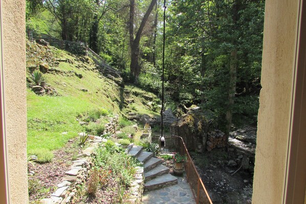 Eine steinerne Treppe führt einen grasbewachsenen Hang hinauf, umgeben von Bäumen.