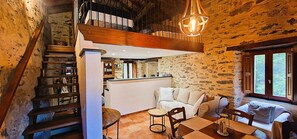 Un interior rústico con una escalera, una zona de comedor y un rincón acogedor para sentarse.