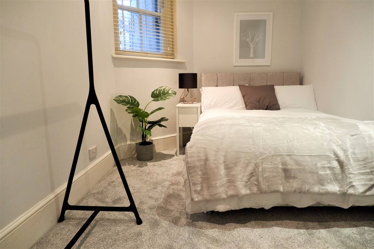 Une chambre à coucher avec un lit, une table de chevet, une lampe et une plante en pot.