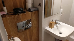 A bathroom with a wooden vanity, a sink with a soap dispenser, and a mirror. - Labo Apartment Metro Plocka (Warsaw)