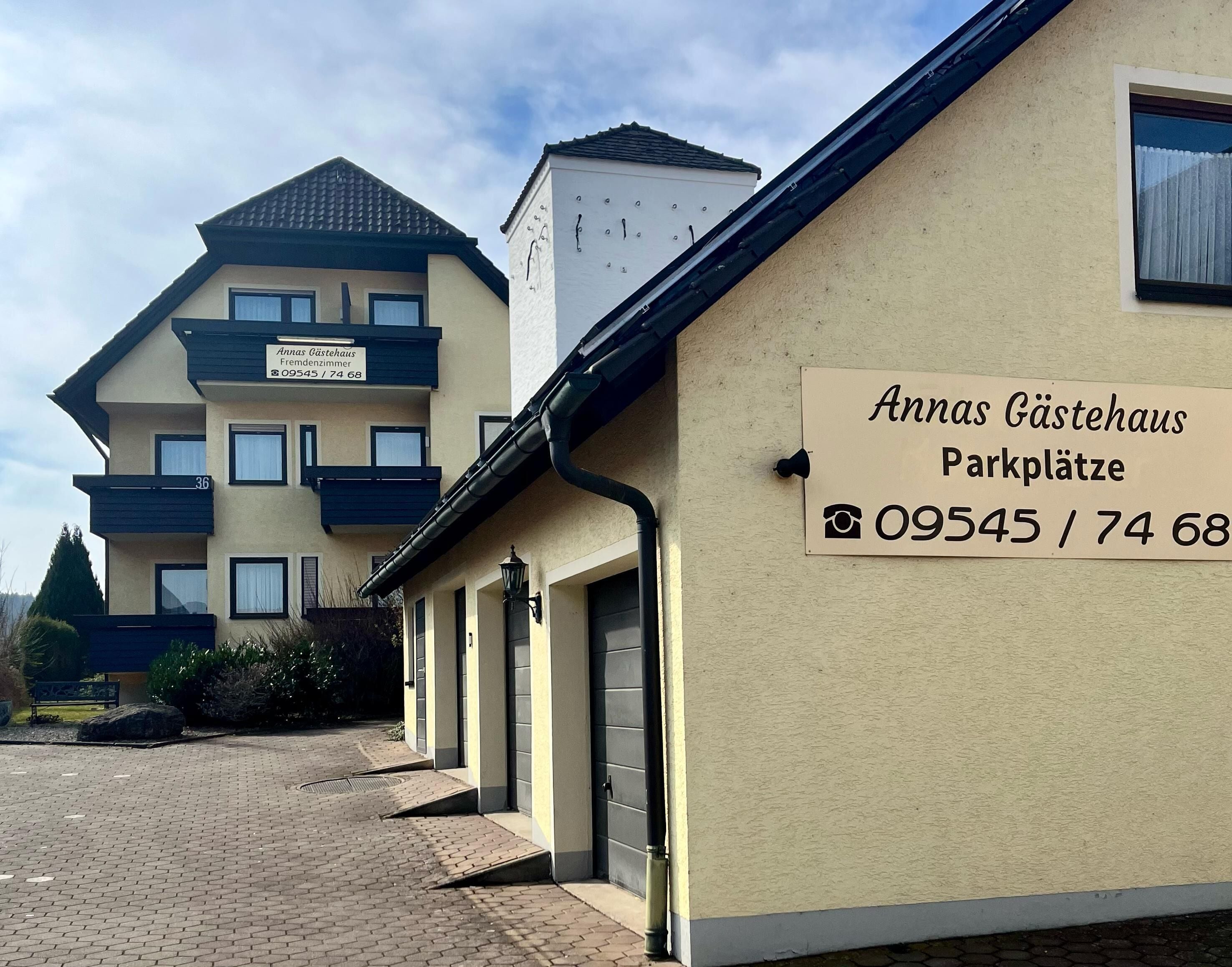 Un bâtiment avec une enseigne indiquant « Anna's Gästehaus – parking » et un numéro de téléphone.