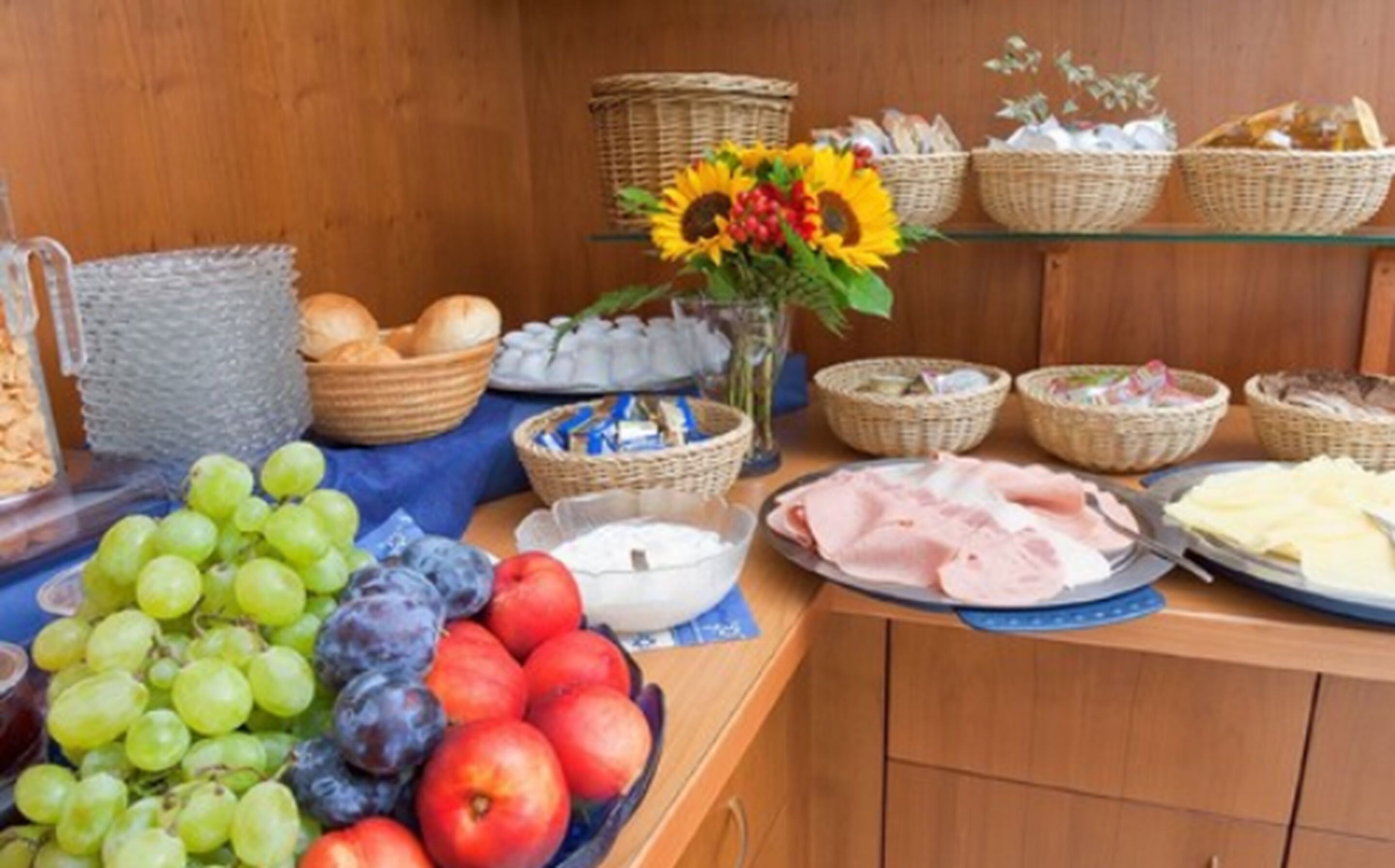 Une table de buffet proposant une variété d’aliments, notamment des fruits, du pain et des pâtisseries.