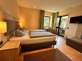 Quarto de hotel moderno com uma cama grande, um sofá, uma escrivaninha e uma televisão.