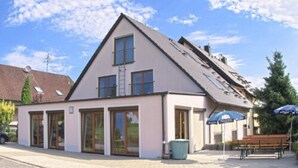 A two-story building with a sloped roof, large windows, and a brick facade. - Annas Gästehaus (Hallerndorf)