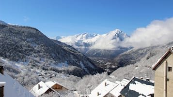 A snow-covered mountain village with traditional wooden houses and a clear view of the mountains in the background.