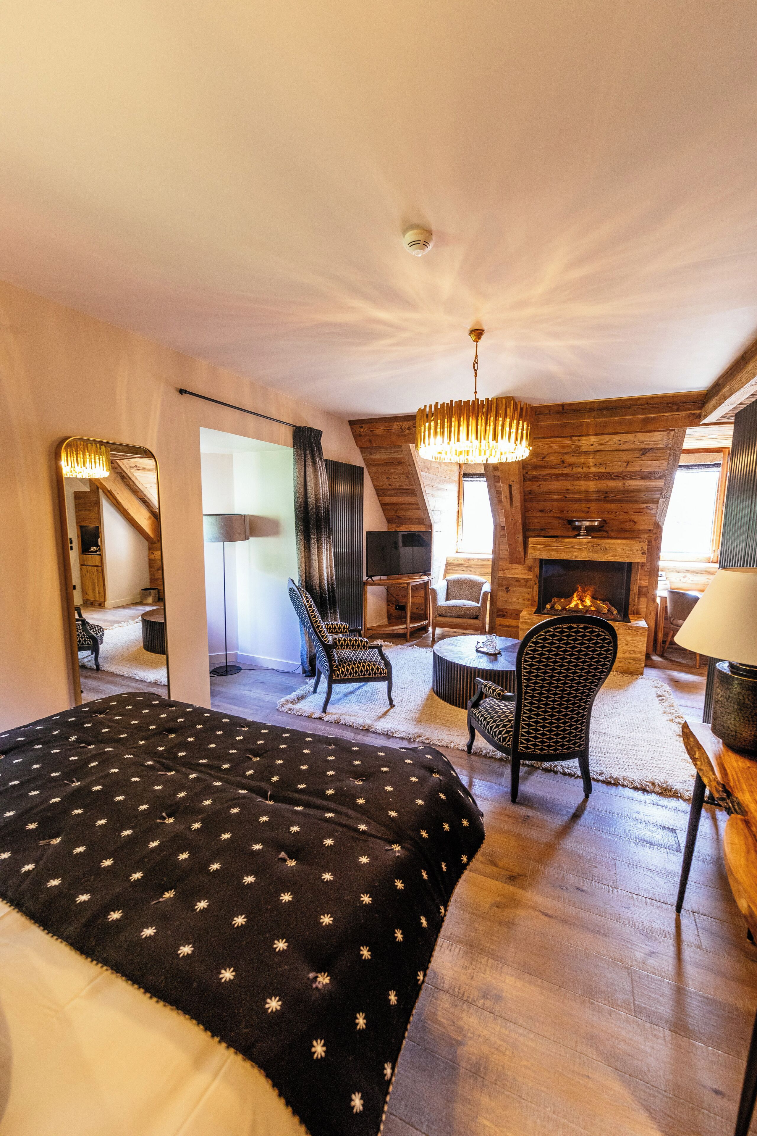 A cozy room with a bed, a fireplace, a television, and a dining area.