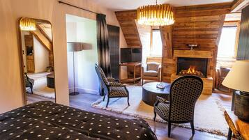 A cozy room with a bed, a fireplace, a television, and a dining area.
