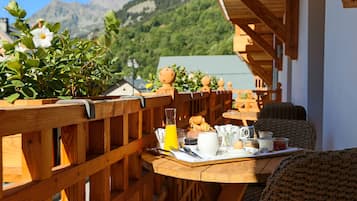 Una terraza de madera con un servicio de desayuno que incluye una bandeja con huevos, tostadas y un vaso de jugo de naranja.