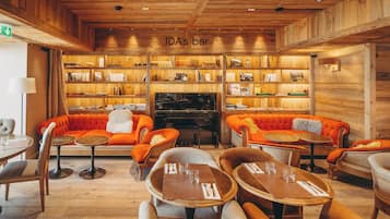 Un rincón acogedor con bar, paredes de madera, sofás naranja y mesas preparadas para comer.