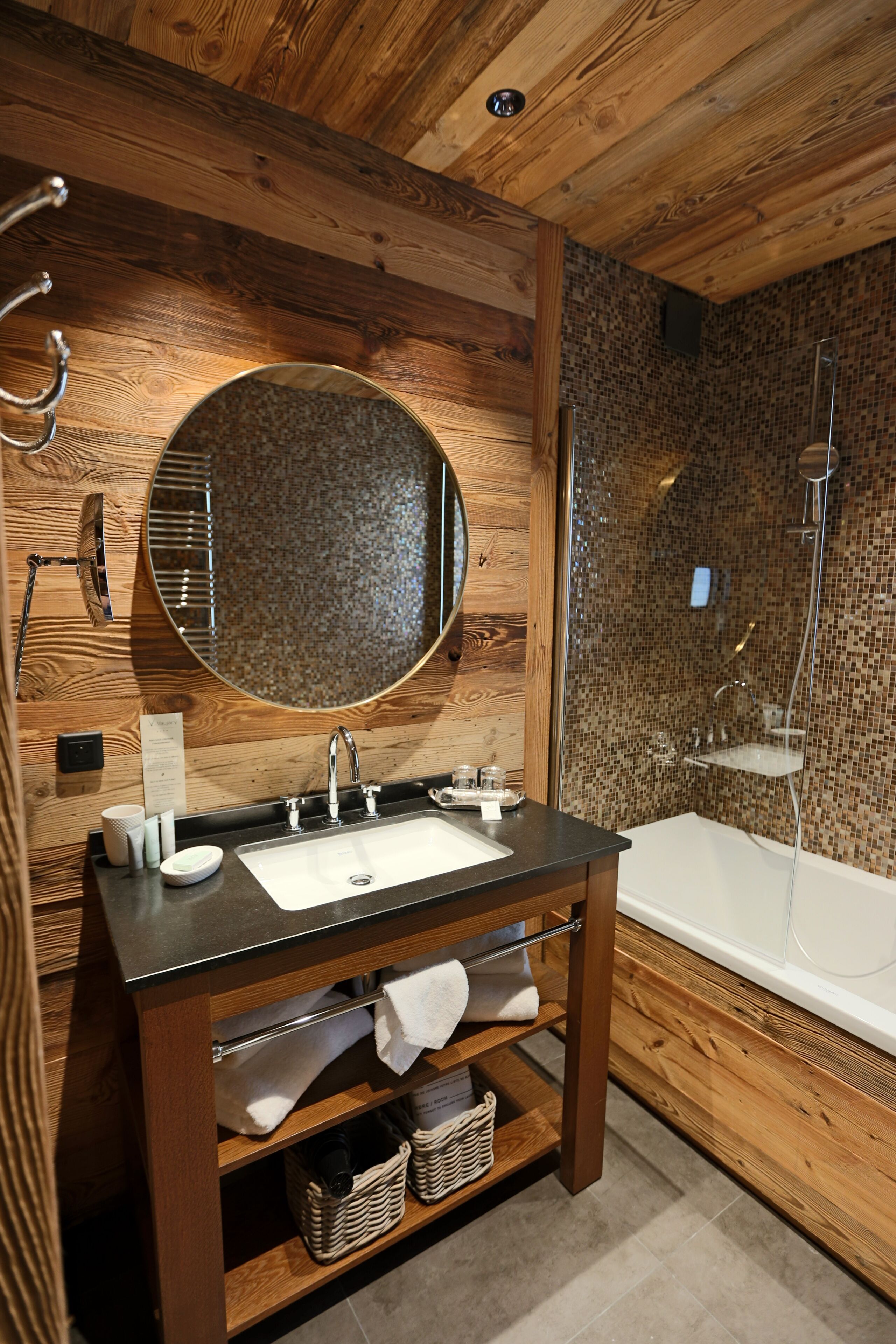 Une salle de bain en bois avec un lavabo, un miroir et une douche.