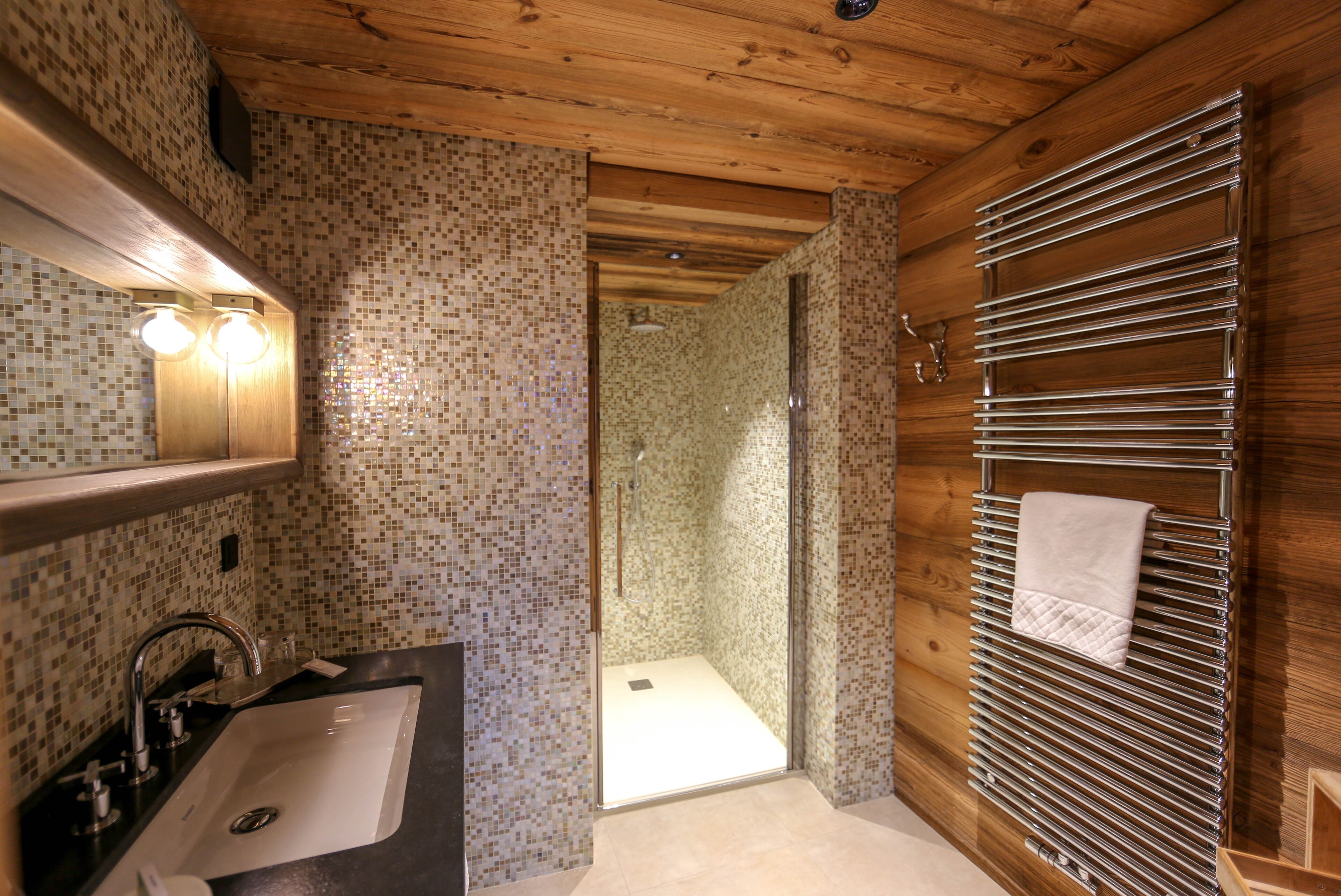 Une salle de bain équipée d’un lavabo, d’un miroir, d’une douche et d’un porte-serviettes.