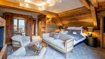 A cozy log cabin bedroom with a large bed, a sofa, and a dining table.