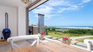 A balcony with a view of the ocean, a barbecue grill, and a blue stove. - Hamilton House (Wilderness)