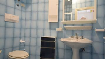 Een douche, een bidet, handdoeken, toiletpapier