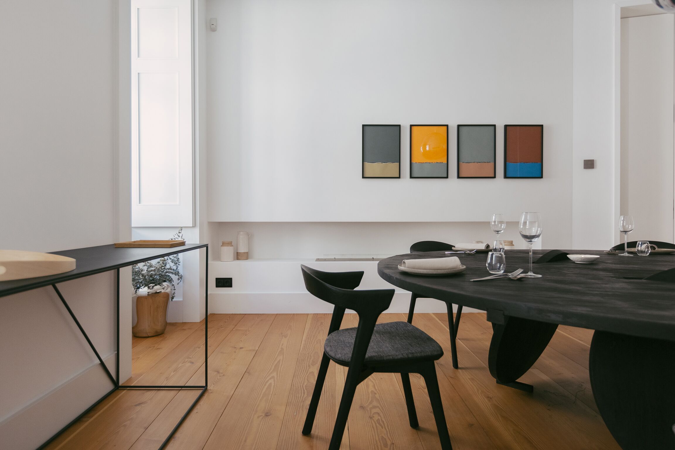 A modern dining area with a round table, black chairs, and a minimalist design.