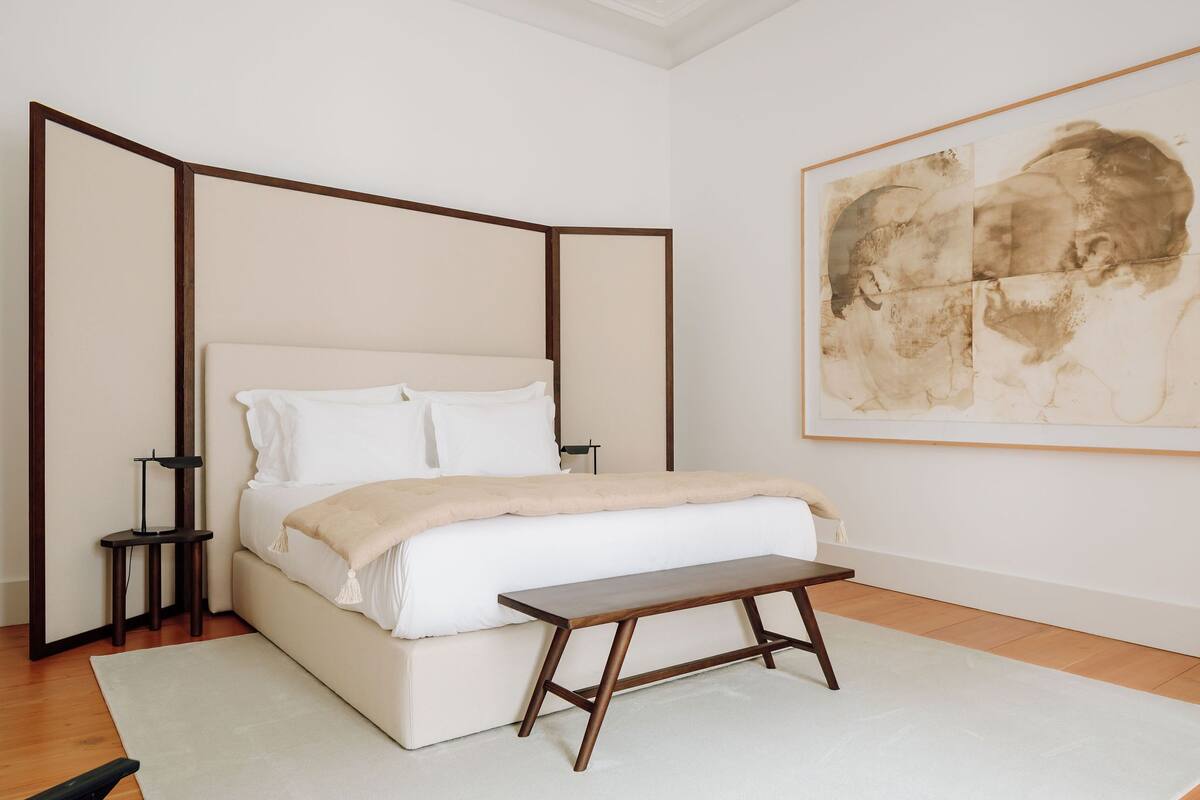 A bedroom with a bed, bedside table, and a large framed artwork on the wall.