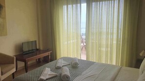 A hotel room with a bed, a chair, a desk with a TV, and a painting on the wall. - Agnanti Villas magnificent view, perfect for families and group up to 15 guests  (Heraklion Crete Agia Pelagia)
