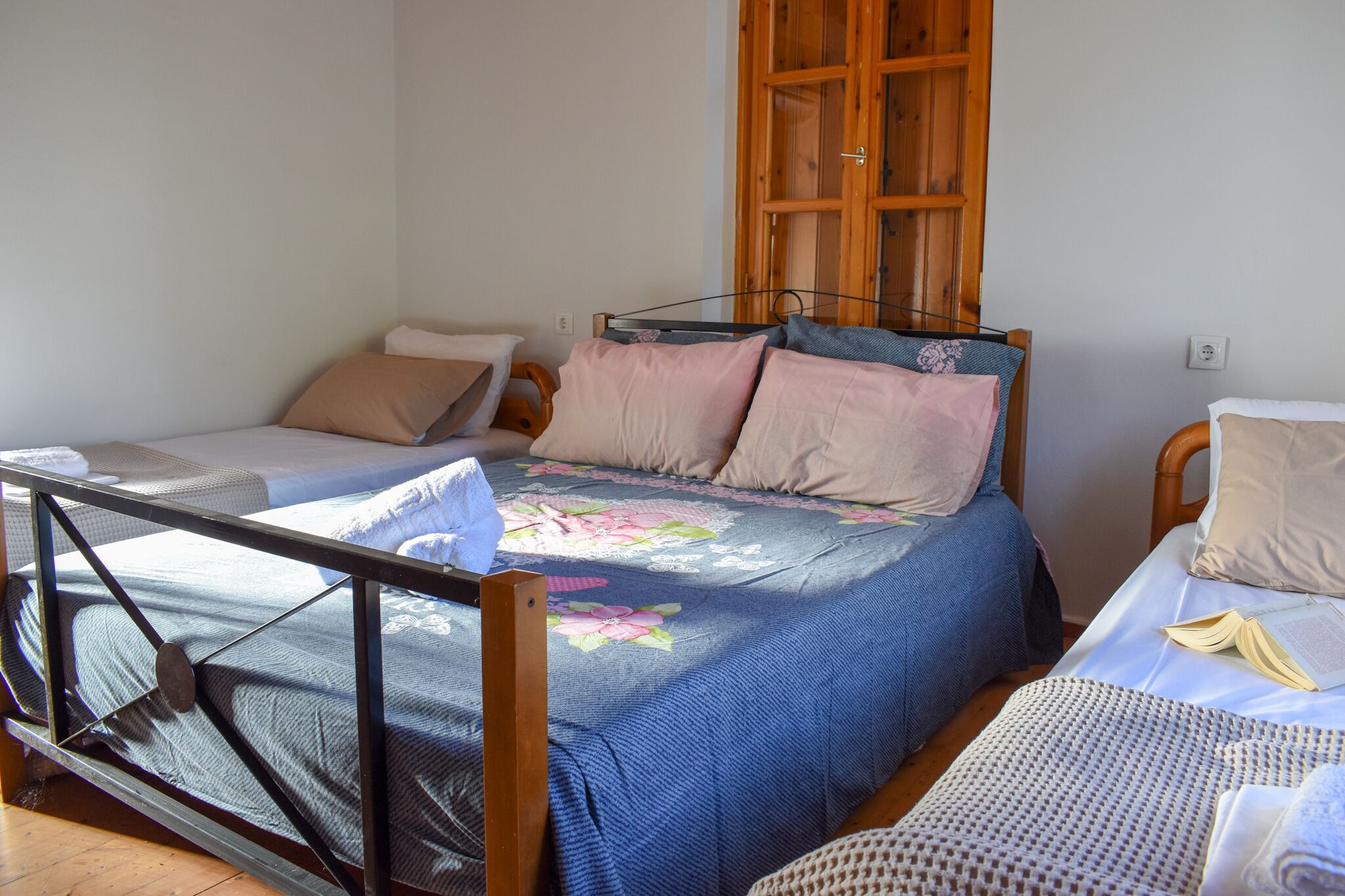 A single bed with a floral bedspread, a wooden headboard, and a small bedside table with a book.