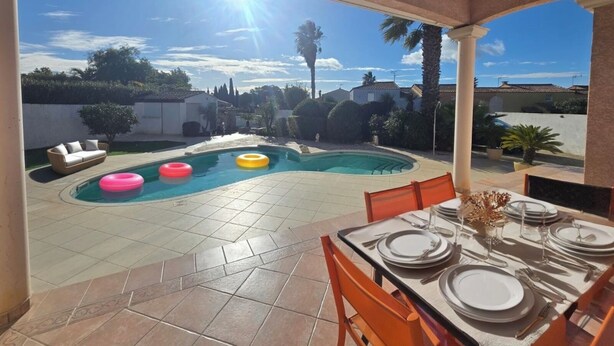 A covered outdoor patio with a pool, dining table set for four, and a view of the neighborhood. - Mediterranean-style villa with pool (Agde)