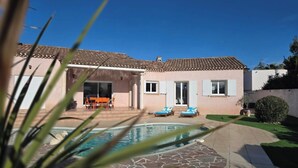 A two-story house with a tiled roof, a swimming pool, and a patio area with lounge chairs. - Mediterranean-style villa with pool (Agde)