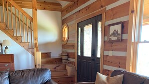 Een gezellige woonkamer met een houten trap, leren banken en een tapijtend.