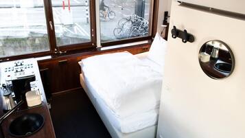 Una cabaña compacta con cama, una kitchenette pequeña y una ventana con un soporte para bicicletas afuera.