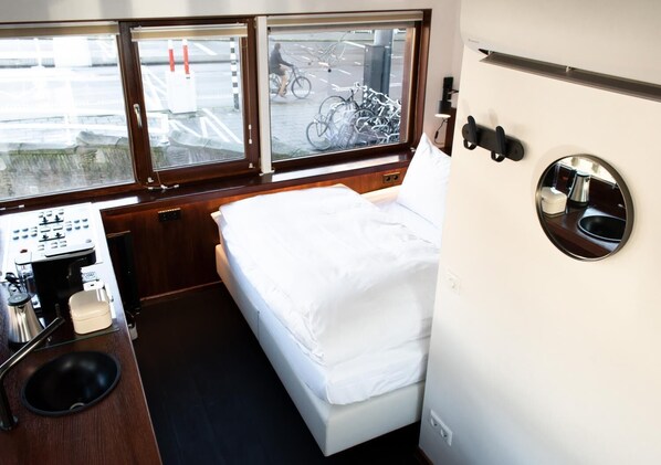 A compact cabin with a bed, a small kitchenette, and a window with a bicycle rack outside.
