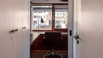 Un espacio de oficina moderno con un escritorio y una silla, ventanas amplias con vistas a bicicletas y edificios.